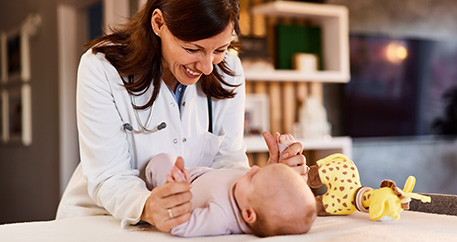 Ärztin mit Stethoskop untersucht Baby